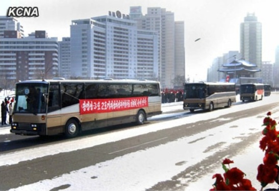 Buses transporting rocket launch personnel ride past  the Pot'ong Gate, at the intersection of Ch'angkwang and Ch'o'llima Streets in central Pyongyang on 4 January 2013 (Photo: KCNA)