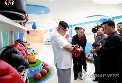 Kim Jong Un tries on a boxing glove looking at productions of the Pyongyang Sports Apparatus Factory (Photo: KCTV-Yonhap).